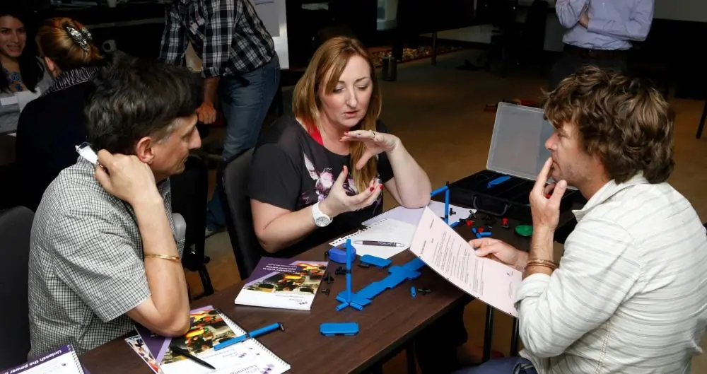 Participants discussing the MTa Mini kit at a masterclass, focusing on team communication and project planning.