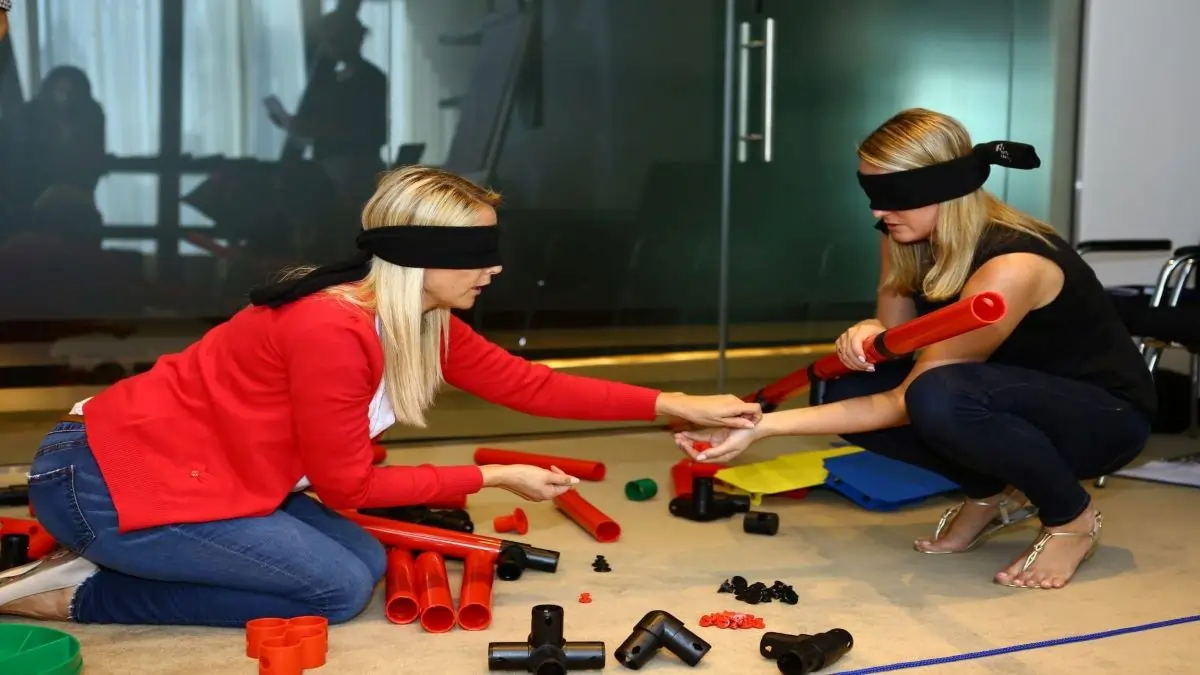 Blindfolded participants engage in MTa activity, enhancing communication and trust in teams.