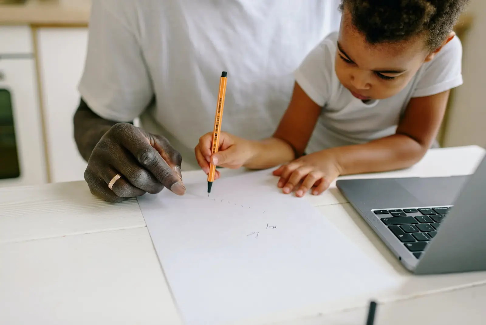 A child sketching a design for a table, actively engaged in brainstorming and planning features for a functional, extendable table in a group-based STEM activity.