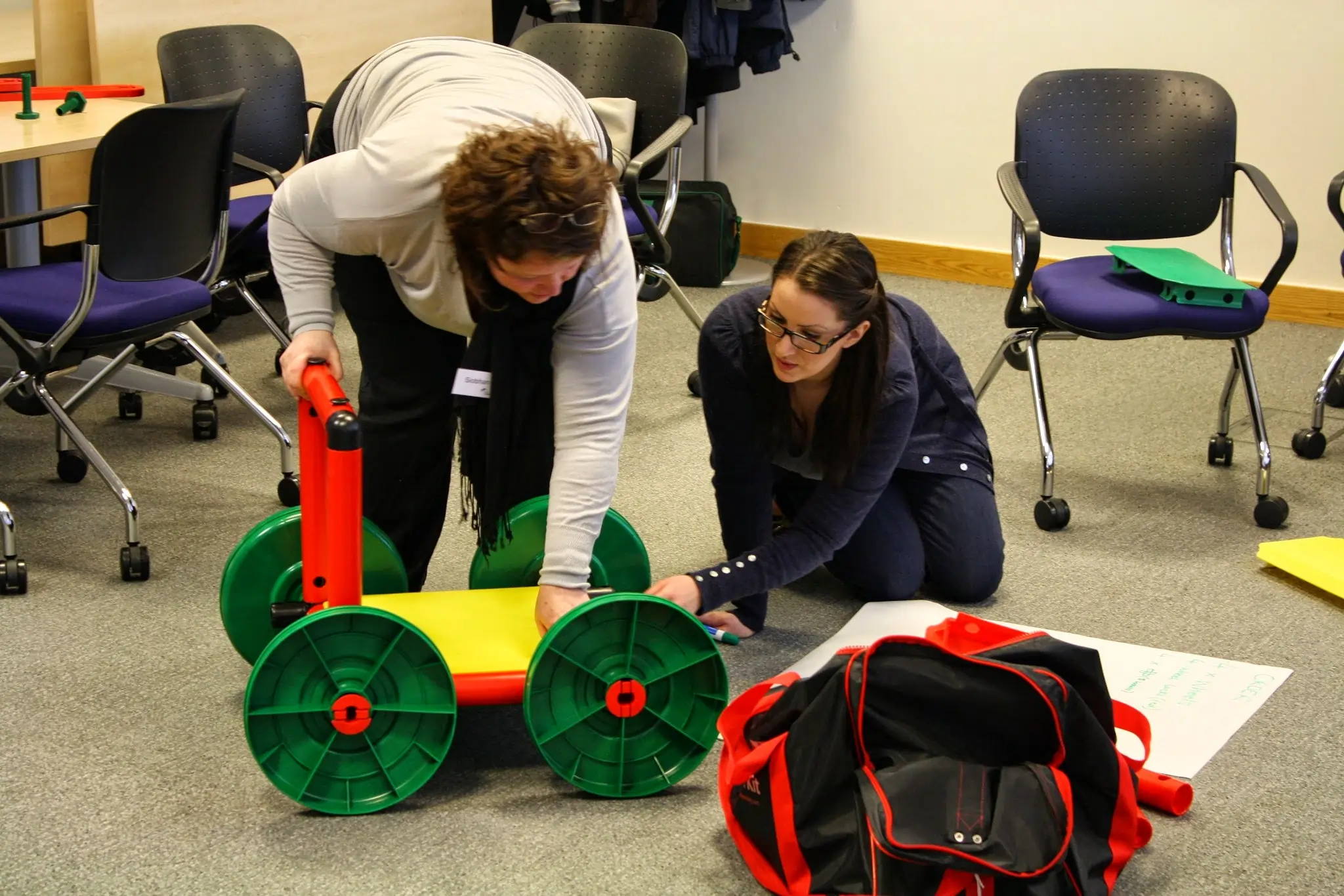 Two participants engaging in 'The Trailer' activity, practicing teamwork and leadership skills in a collaborative project.